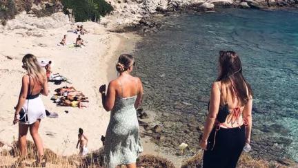 Topdeck travellers walking down a path down to a sandy beach on the coast of Greece during their sailing trip.