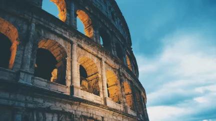 A view of the Colosseum of Rome during dusk, it's exterior lit up.
