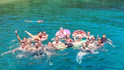 Topdeck travelers swimming and frolicking in the clear blue waters of Limani Bay in Turkey.