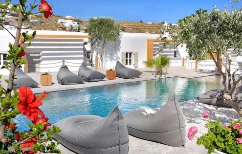 Stylish beanbags and bright white walls line the sparkling waters of a swimming pool in Pentinos.