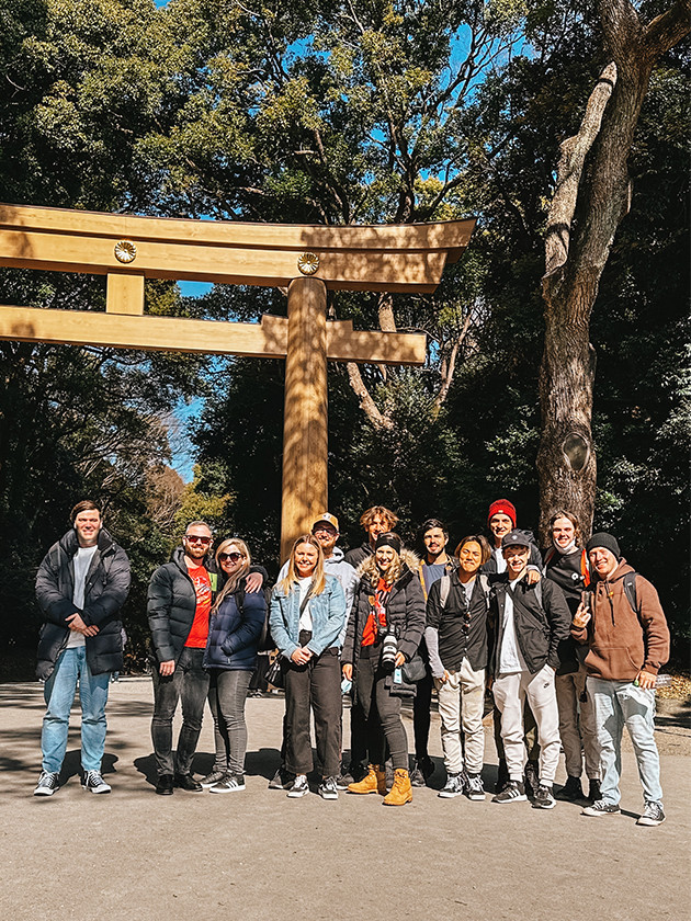 Topdeck travellers posing for a group photo in front of the gate to the Meiji Shrine.