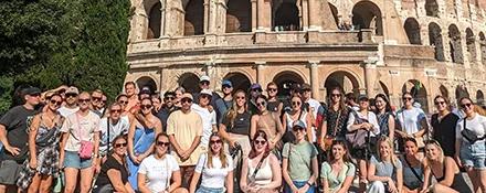 Topdeck tour group taking a picture together in front of the Colosseum of Rome.